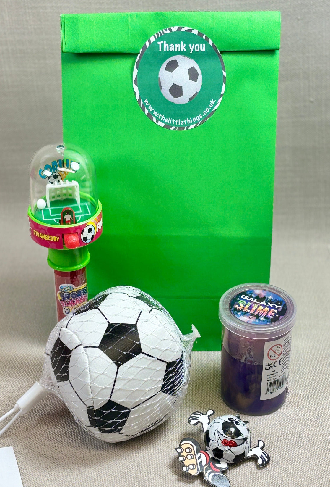 Green Paper party bag with a football sticker. Includes a soft stitch football, tube of time, a sports flicker Looy sweet, and chocolate football.