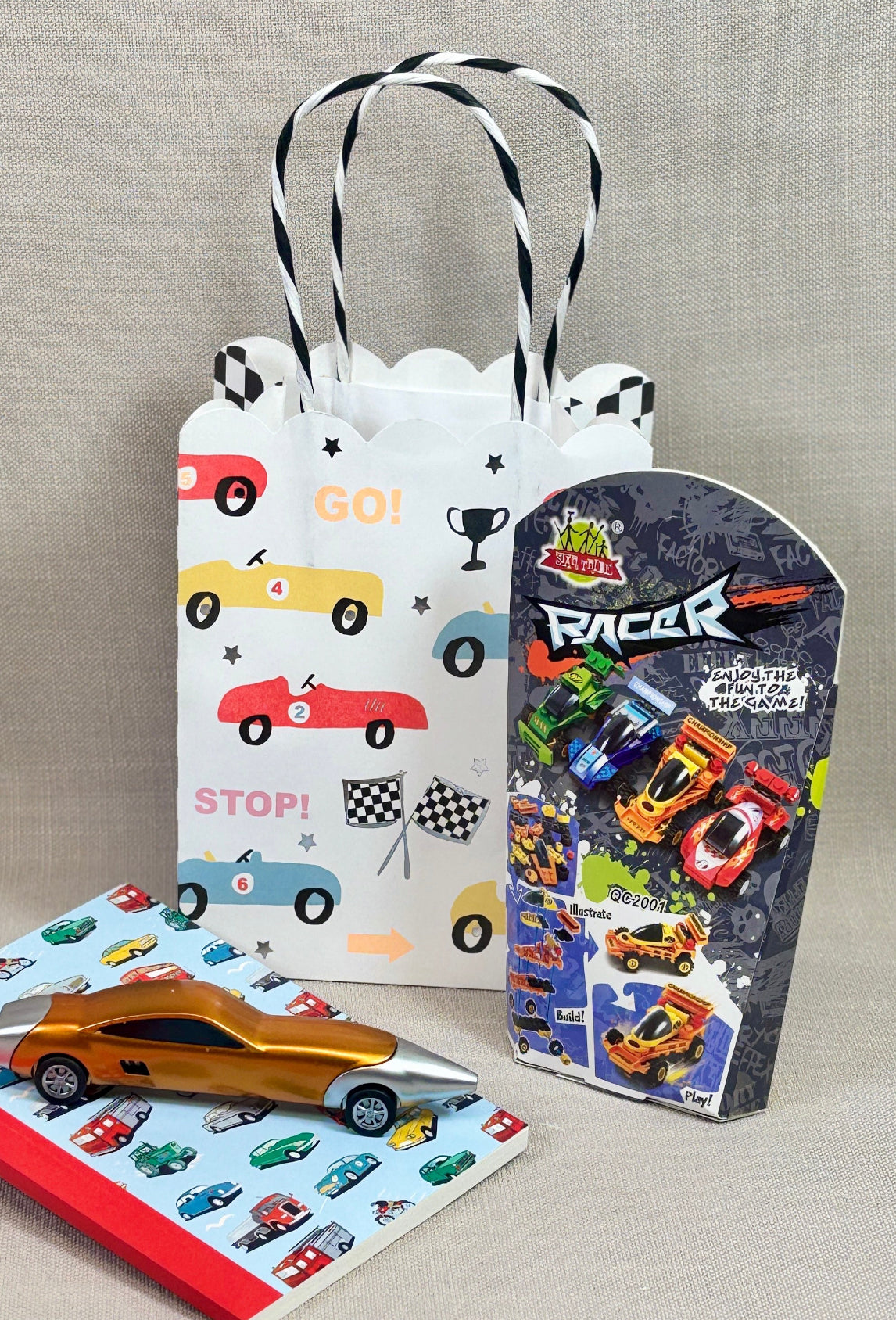Children's gift bag with car-themed design on. Included with the bag is car bricks, notebook and pen.