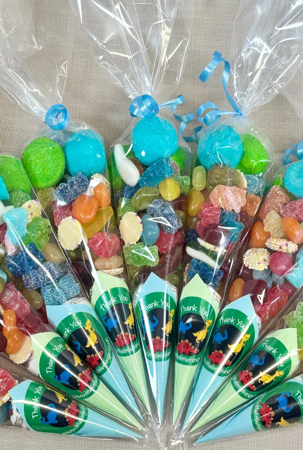 Assorted colorful candies in clear plastic cones on a gray background