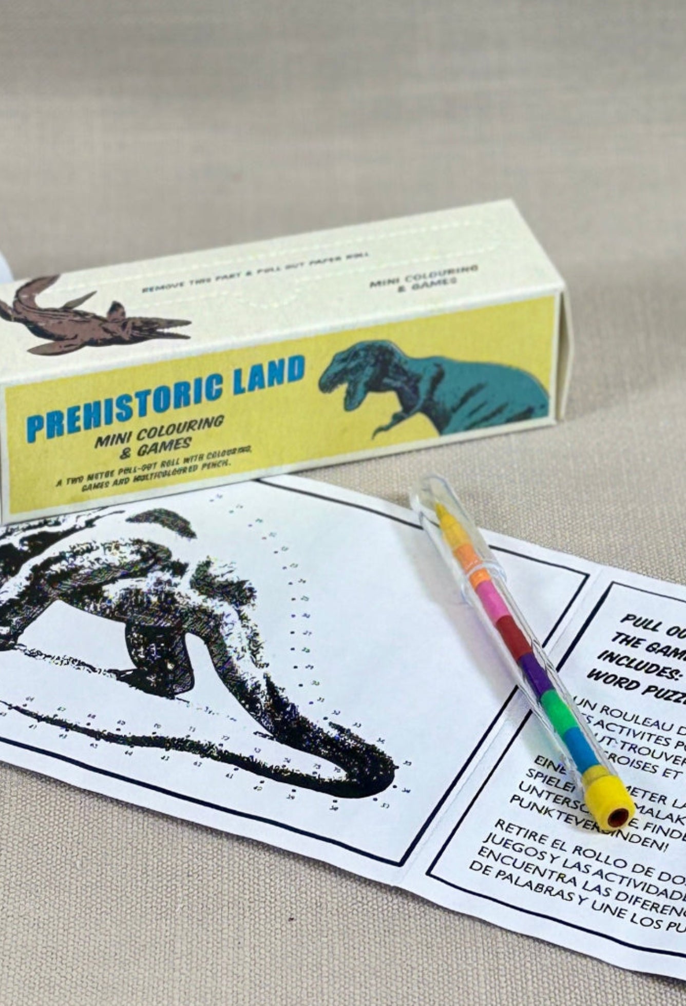 Educational kit with prehistoric animal model, paper, and pencil on a beige background
