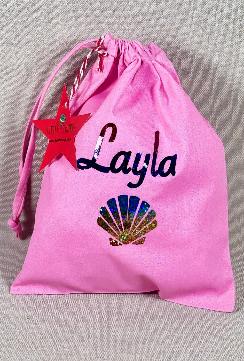 Pink drawstring bag with 'Layla' and a shell design on a gray background