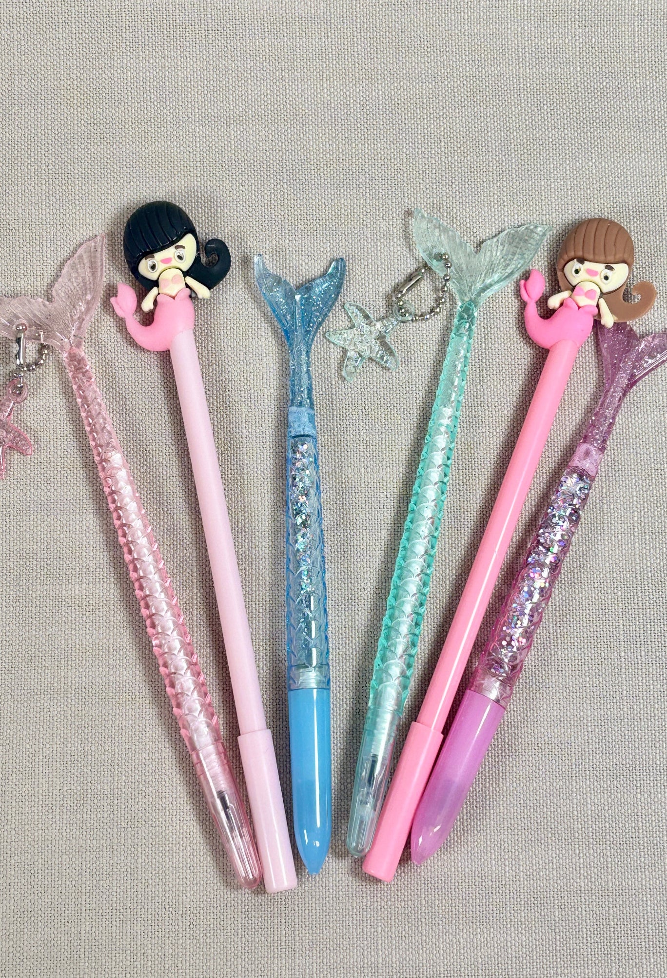 Mermaid pens with cartoon character ends on a textured surface