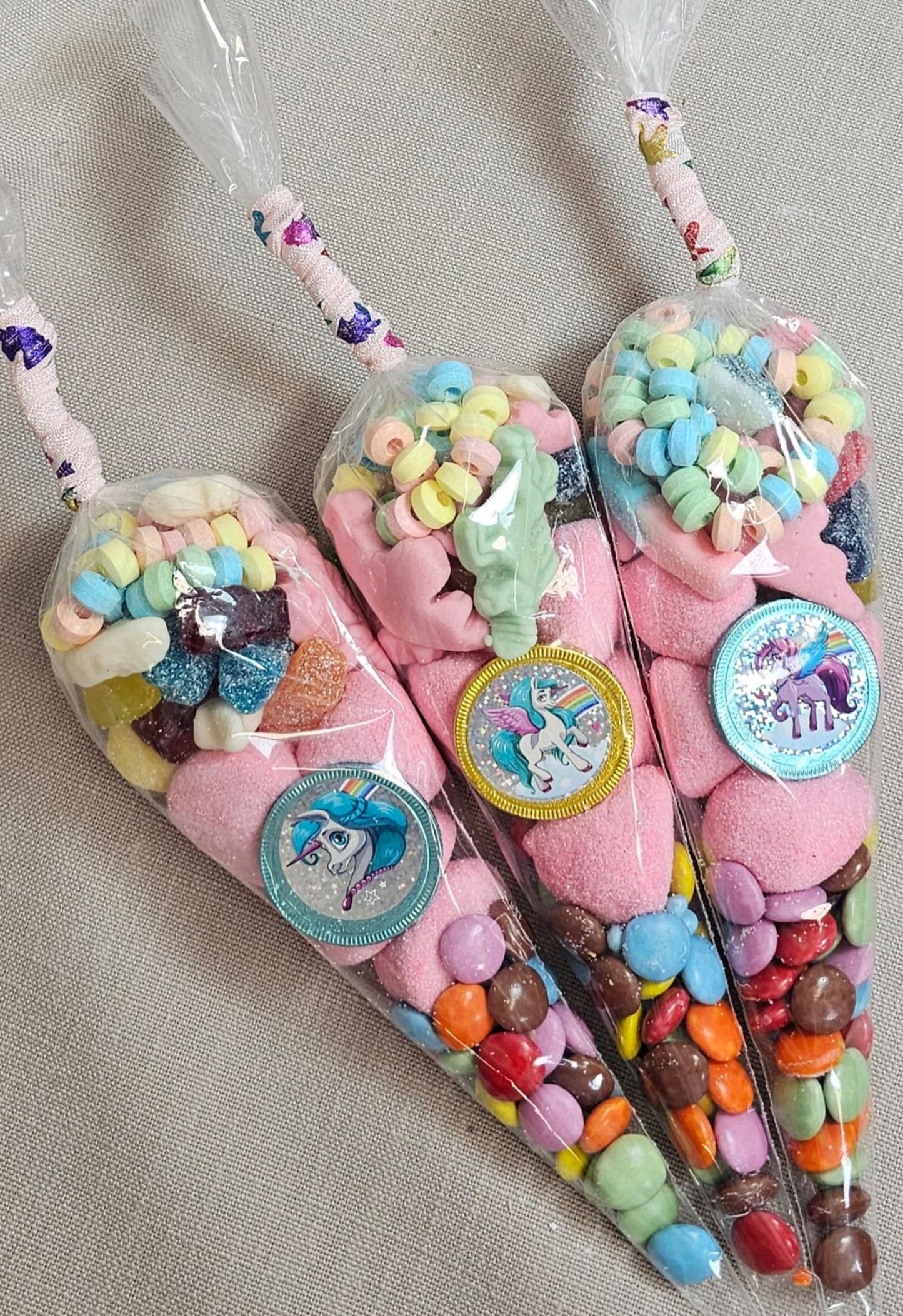 Pre-filled sweet cones designed to look like unicorn horns, filled with various colorful candies and decorated with unicorn-themed ribbons.