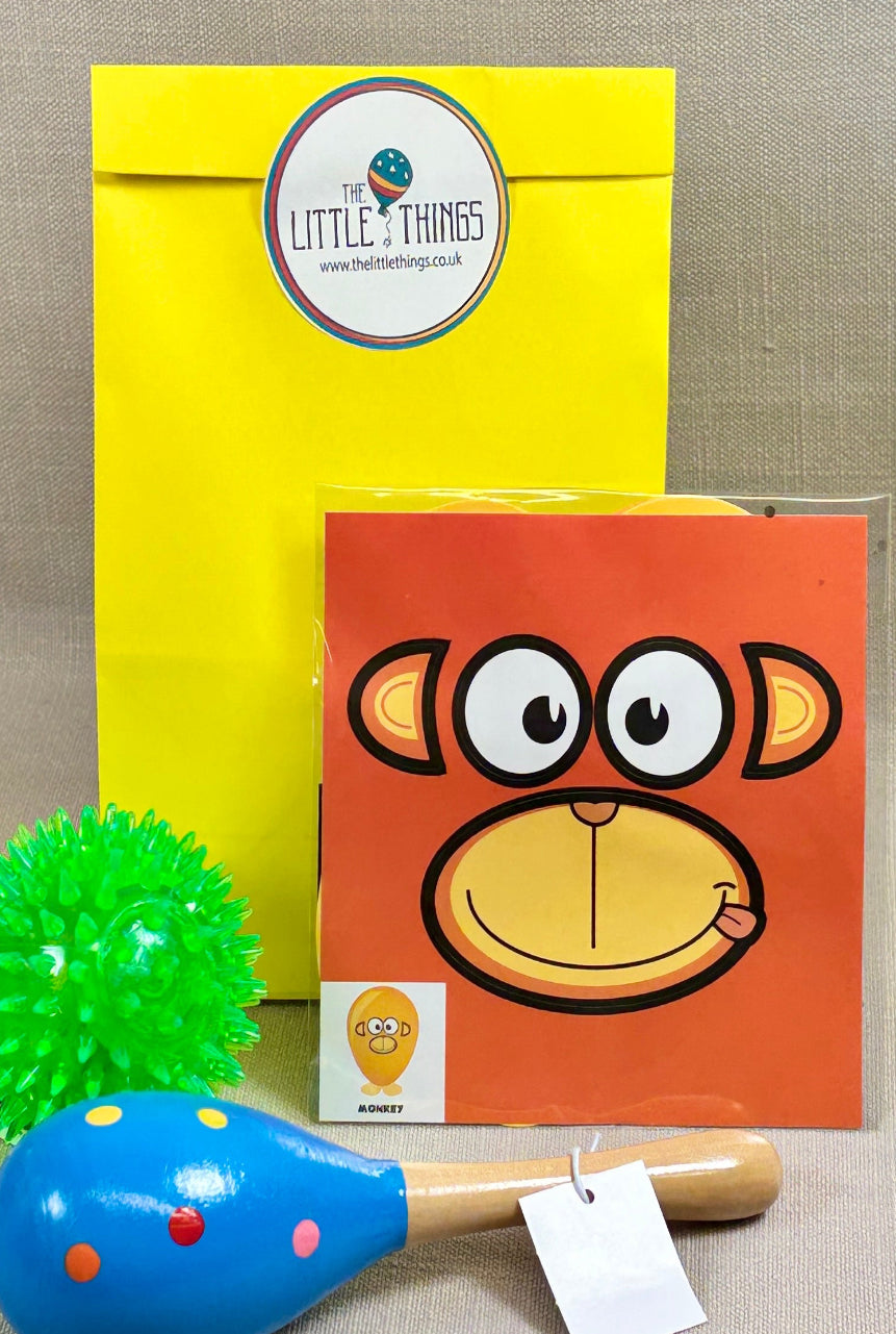 Yellow paper party bag with sticker. Includes a light up ball, maraca, and a ballon animal face toy. Perfect for unisex younger kids party. 