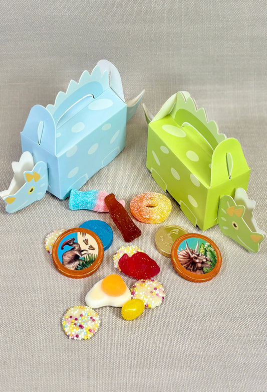 Two dinosaur-shaped candy boxes with various candies on a gray background