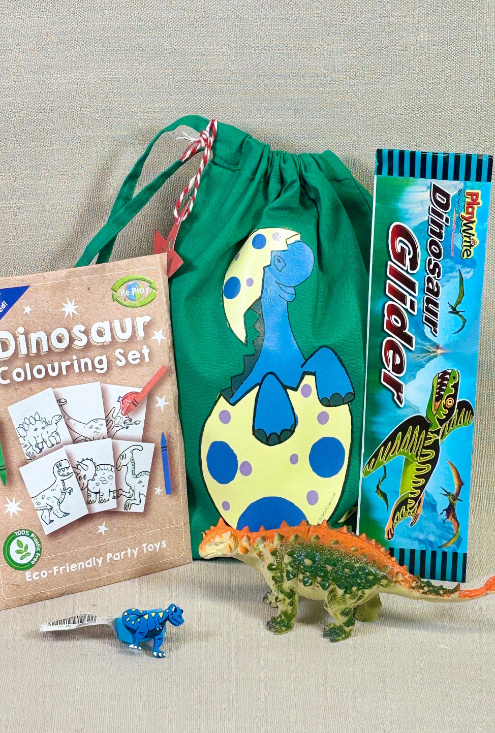 Dinosaur-themed items including a colouring set, a toy, and a snack on a neutral background