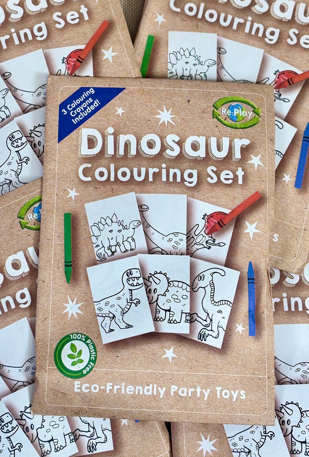Four dinosaur colouring sets with pens on a beige surface