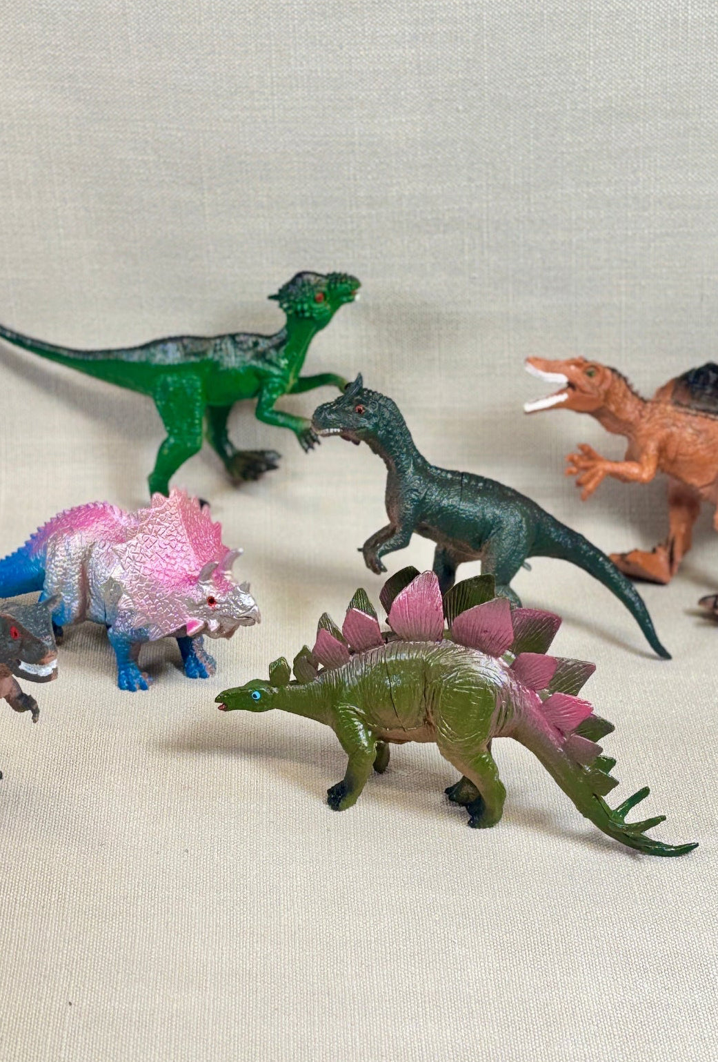 Collection of toy dinosaurs on a light fabric background