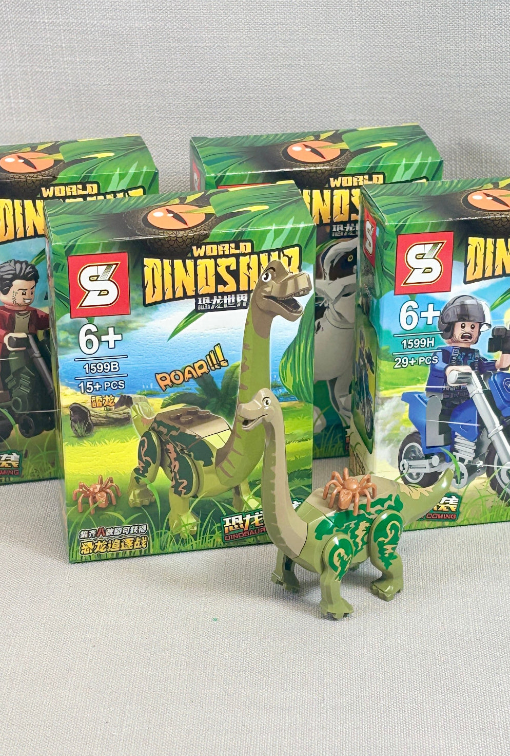 Toy dinosaur figure in front of 'World of Dinosaurs' packaging on a gray background
