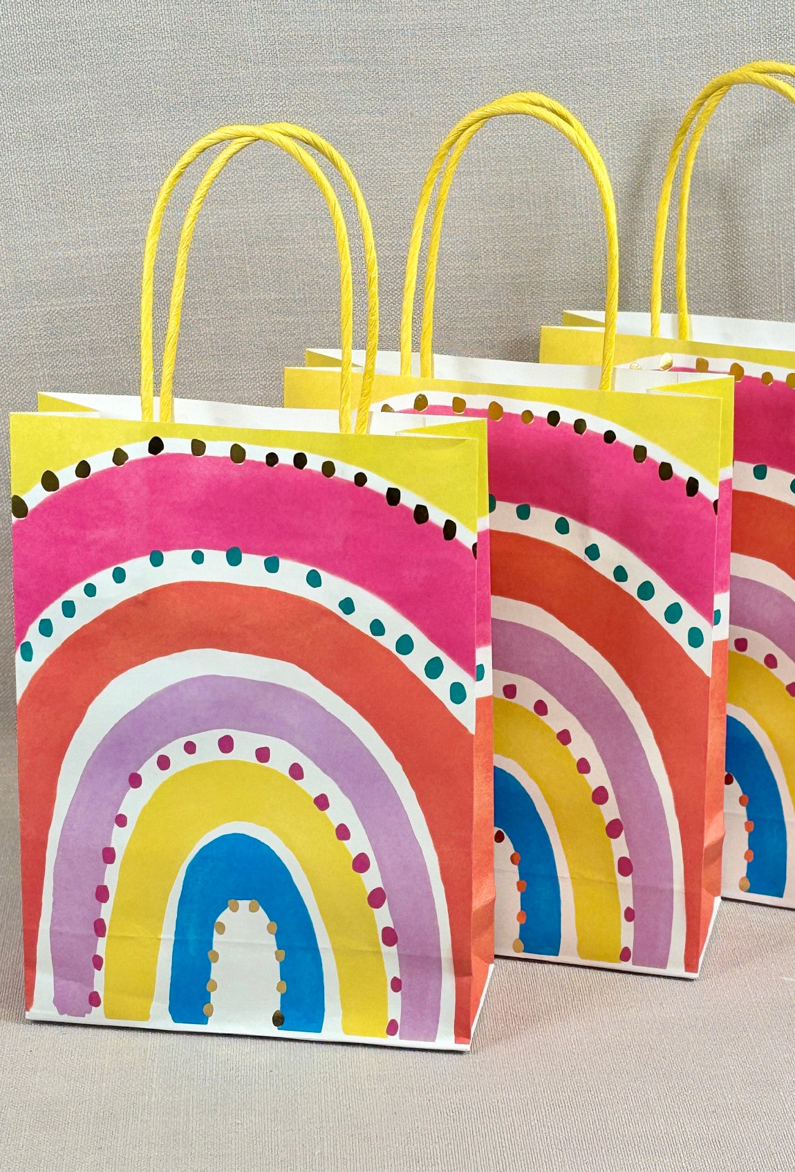 Colorful gift bags with rainbow design on a gray background