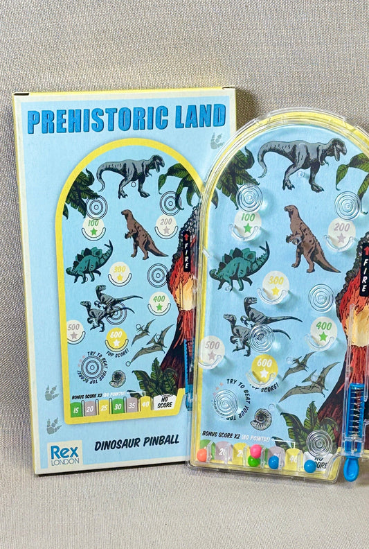 Dinosaur-themed pin ball with packaging on a beige background