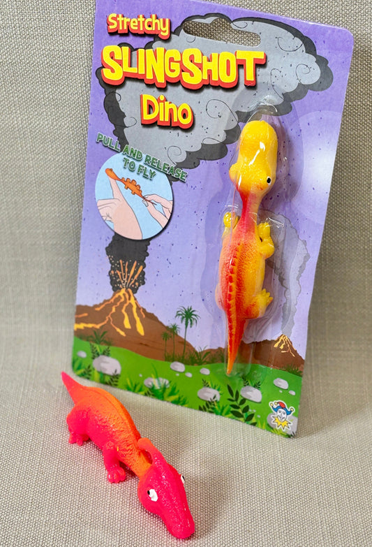 Stretchy slingshot dinosaur toy with packaging on a textured surface