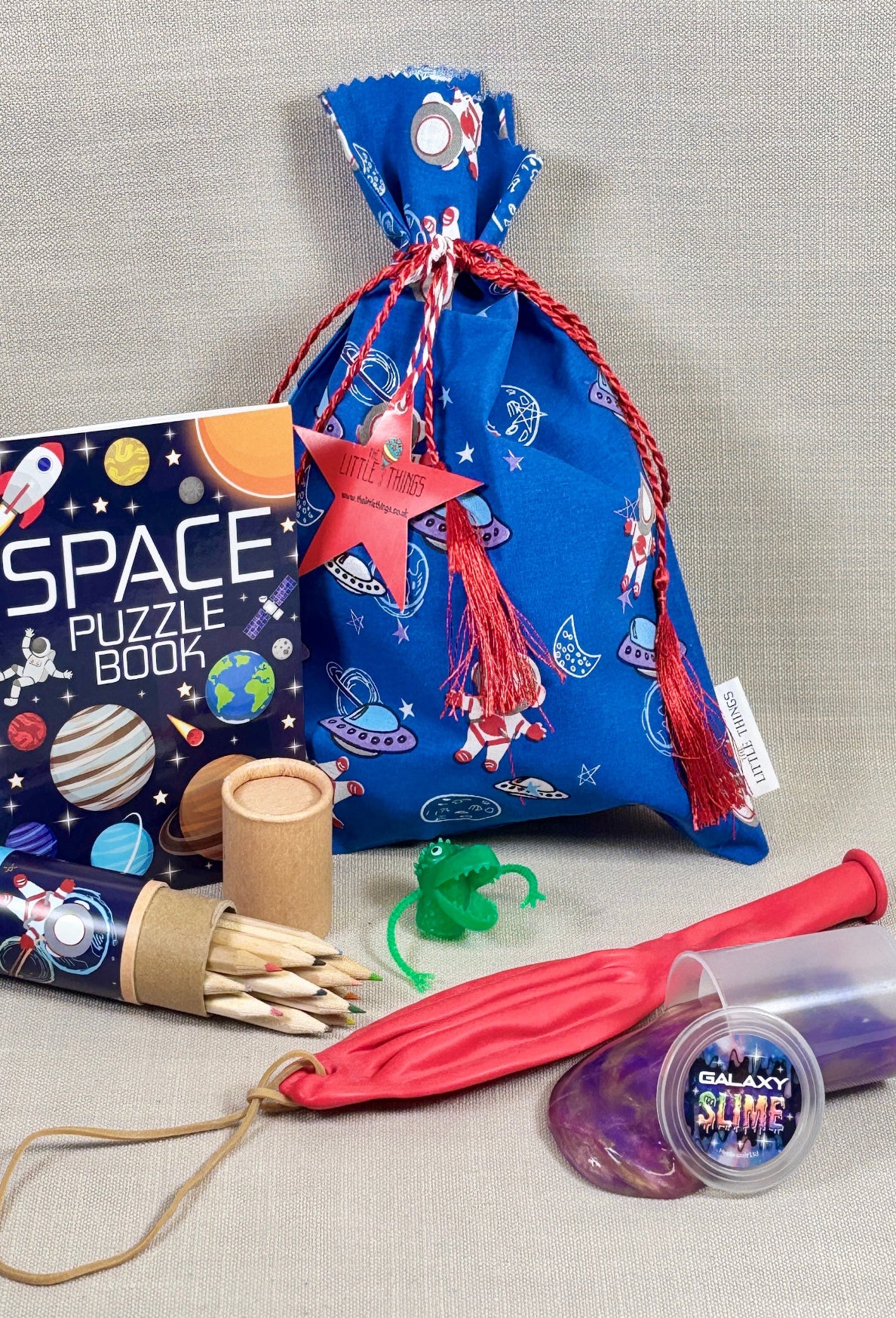Space-themed children's items including a puzzle book, bag, and toys on a gray background