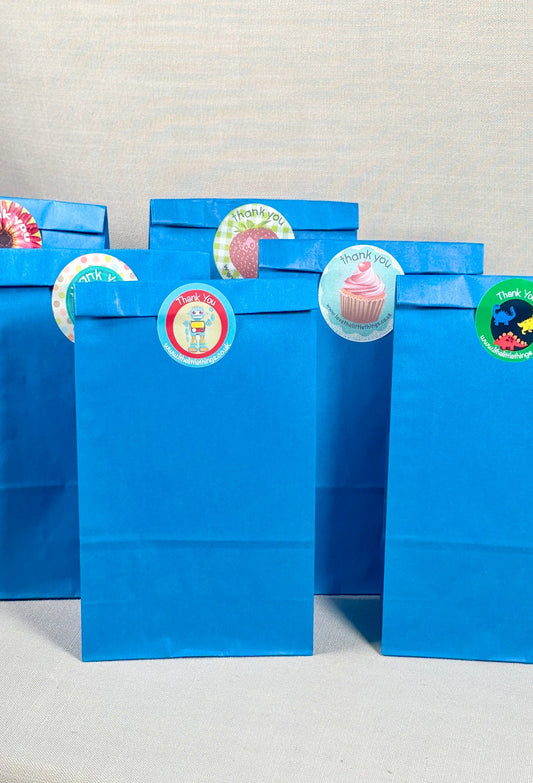 Set of blue gift bags with colorful stickers on a textured surface