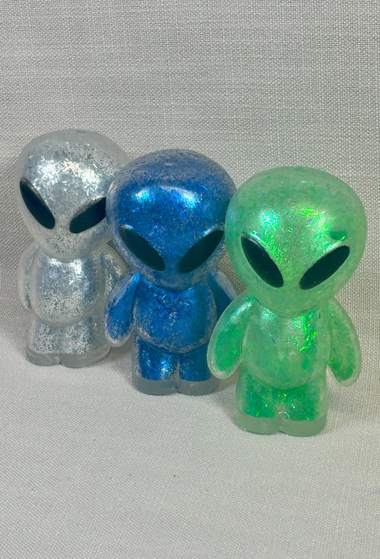 Three colorful alien figurines on a gray background