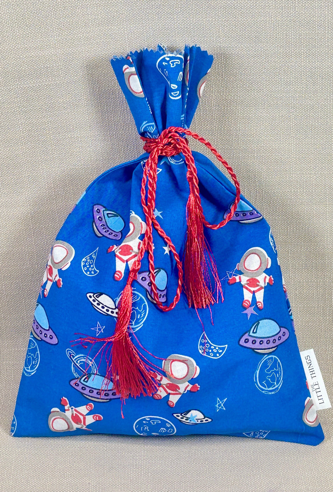 Blue drawstring bag with space-themed design on a gray background