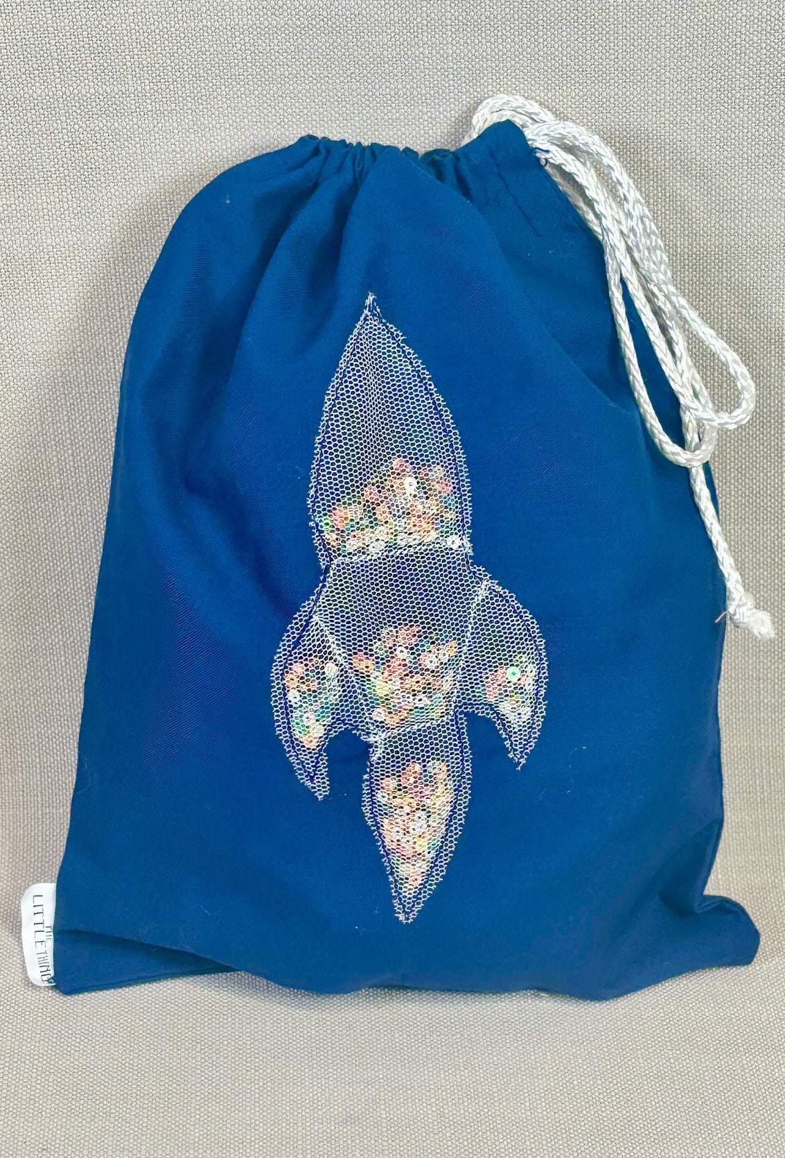Blue drawstring bag with a decorative emblem on a gray background