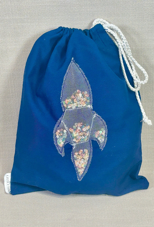 Blue drawstring bag with a decorative emblem on a gray background