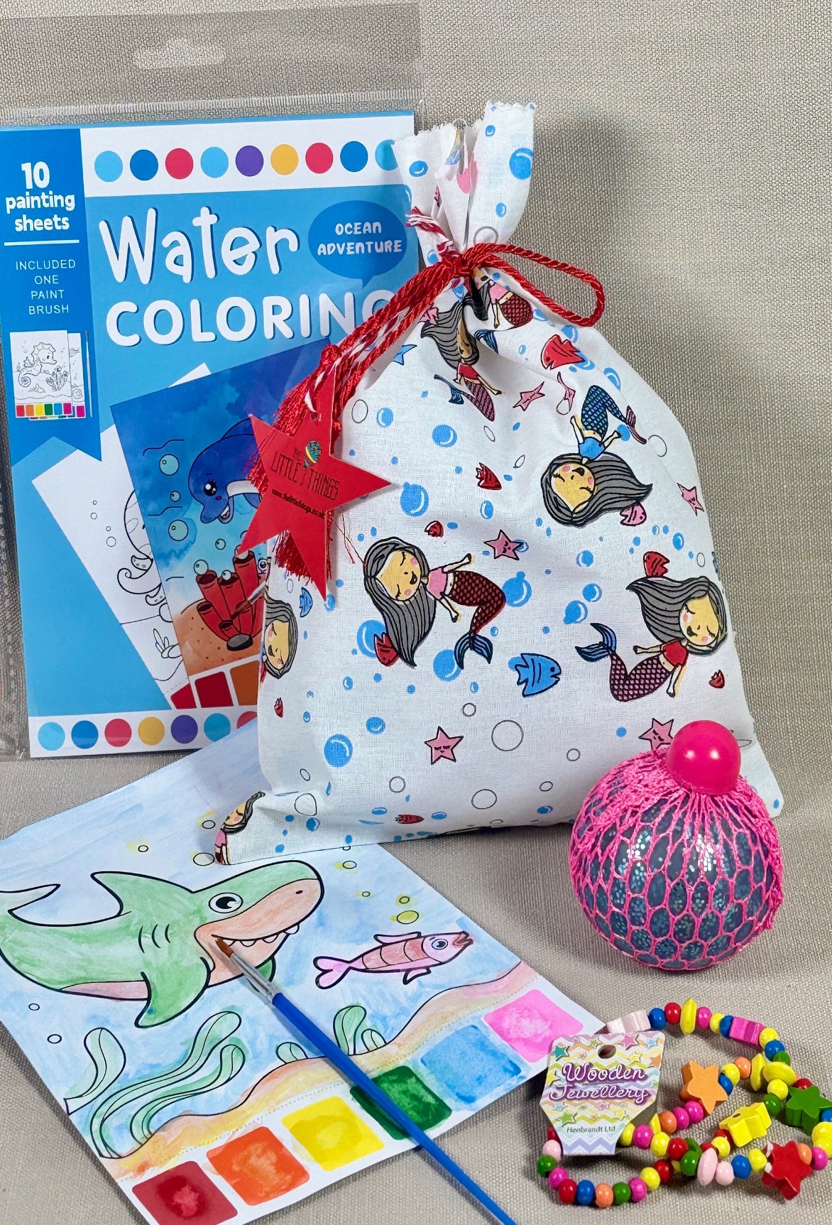 Children's activity kit with water coloring book, beads, and other items on a gray background