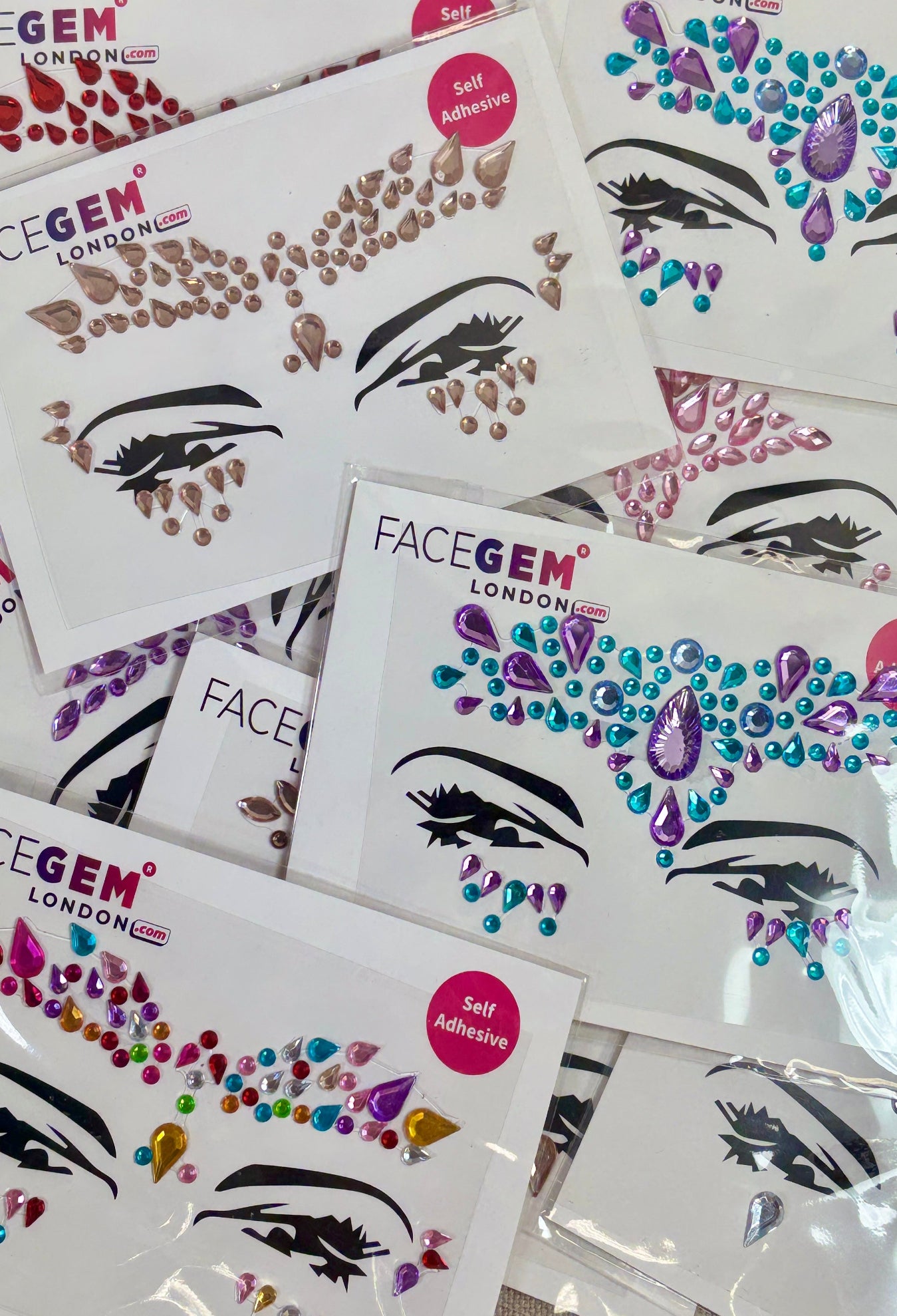Collection of FaceGem London face decal sheets on a textured surface