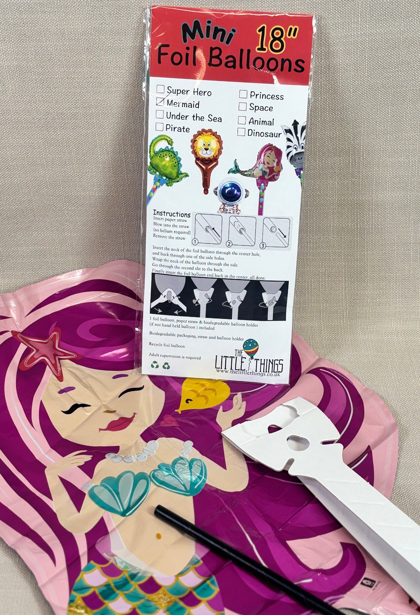 Mermaid-themed foil balloon with packaging and tools on a neutral background