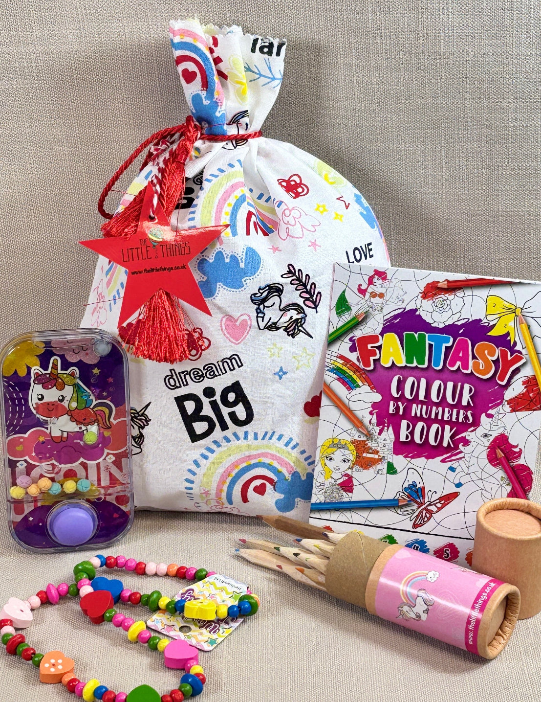 Unicorn fabric party bag with fillers. including at water game, necklace, tube of colouring pencils and an activity book. 