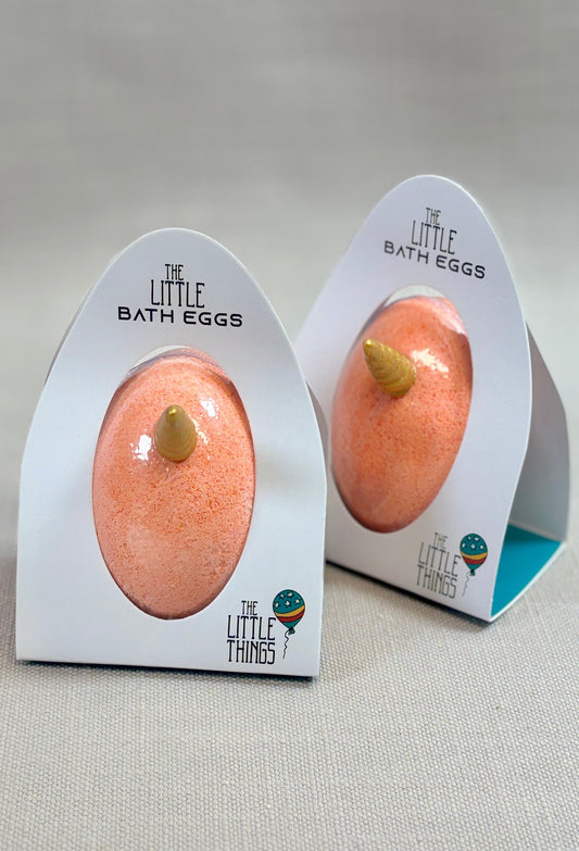 Two peach-colored bath bombs in packaging with 'The Little Things' branding on a neutral background.