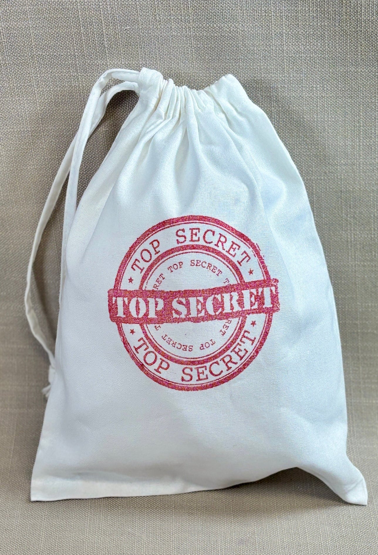 White drawstring party bag with 'Top Secret' stamp. 